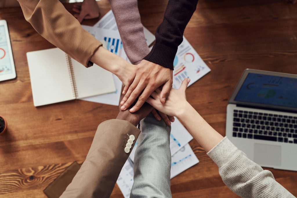 business men and women placing hands together in uniformity