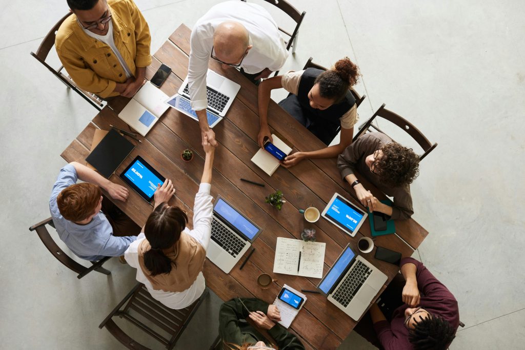 business meeeting with people shaking hands over a large table.